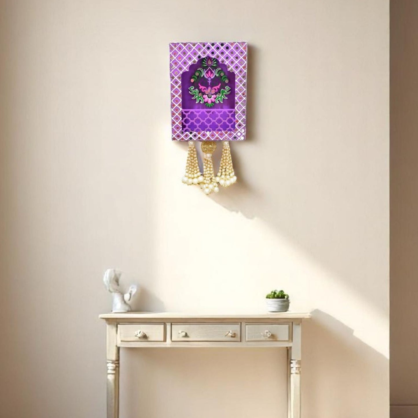 Decorative Jharokha wall hanging with purple and gold design on a beige wall above a white table.