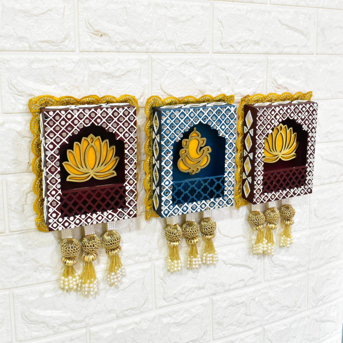 A set of three handmade wall hangings featuring Lord Ganesha with a lotus flower design, in blue, brown, and gold colors, with decorative elements.