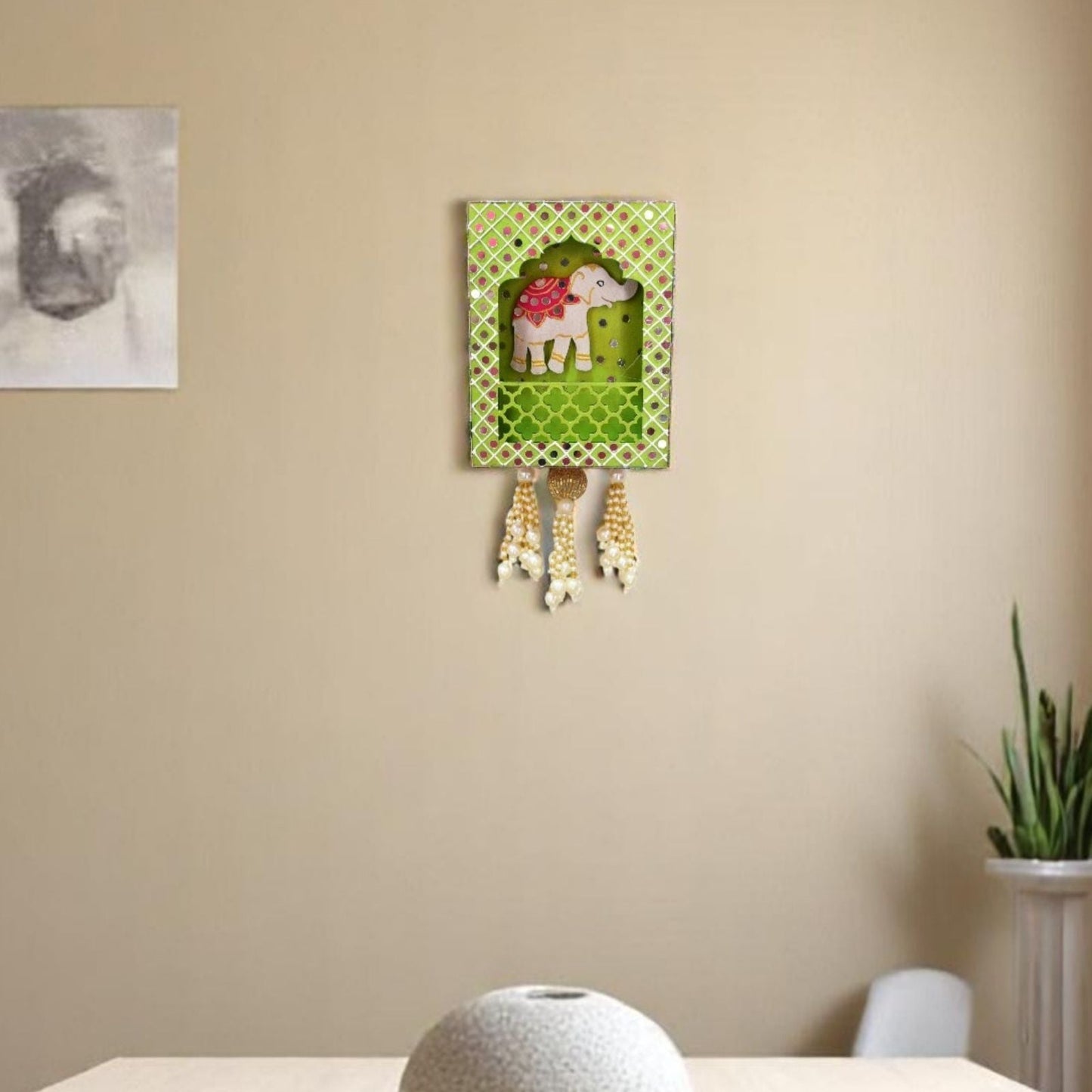 Decorative wall hanging with a green background and white elephant design on a beige wall.