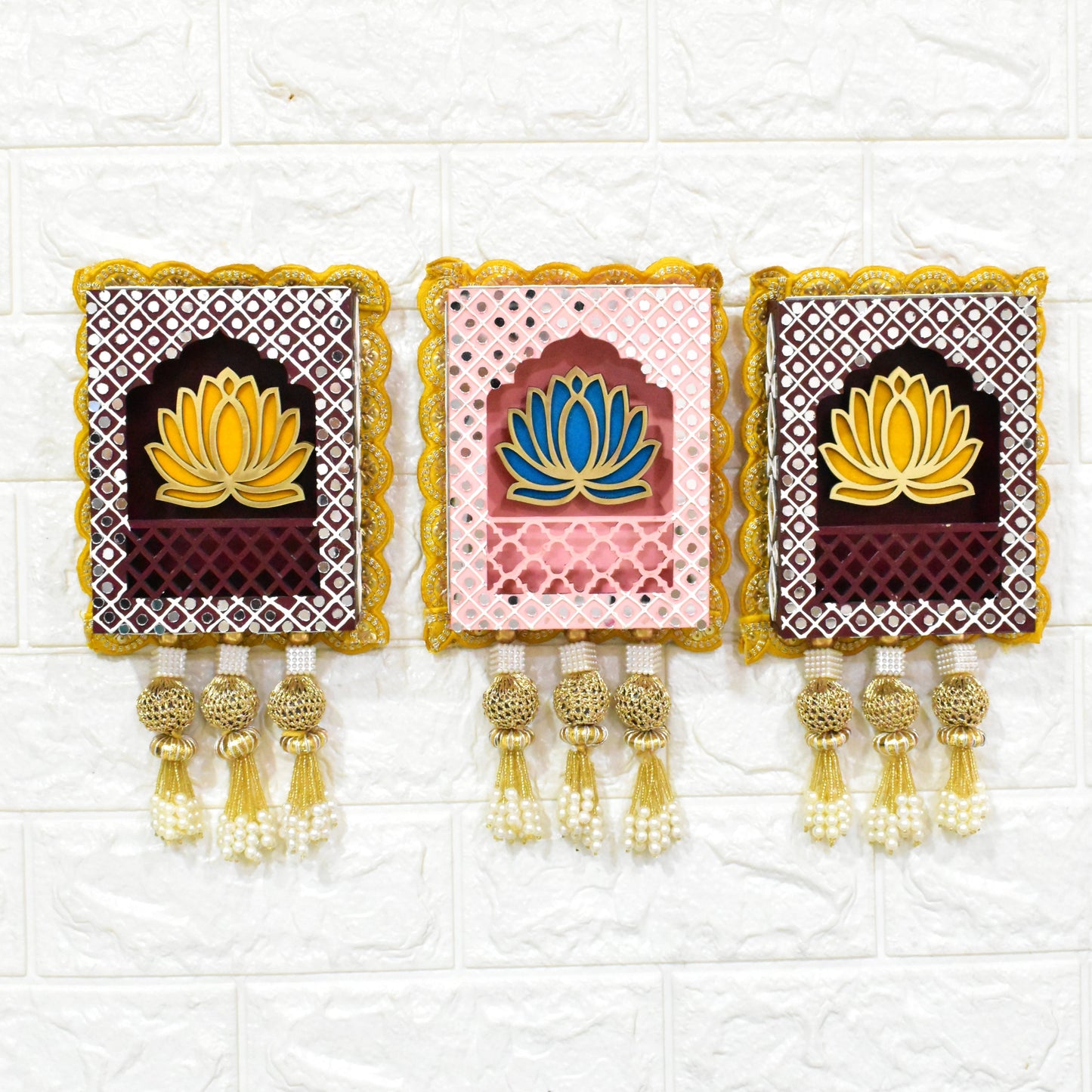 Three rectangular Indian jharokha wall hangings with lotus motifs, decorative patterns, and tassels, displayed against a light background.
