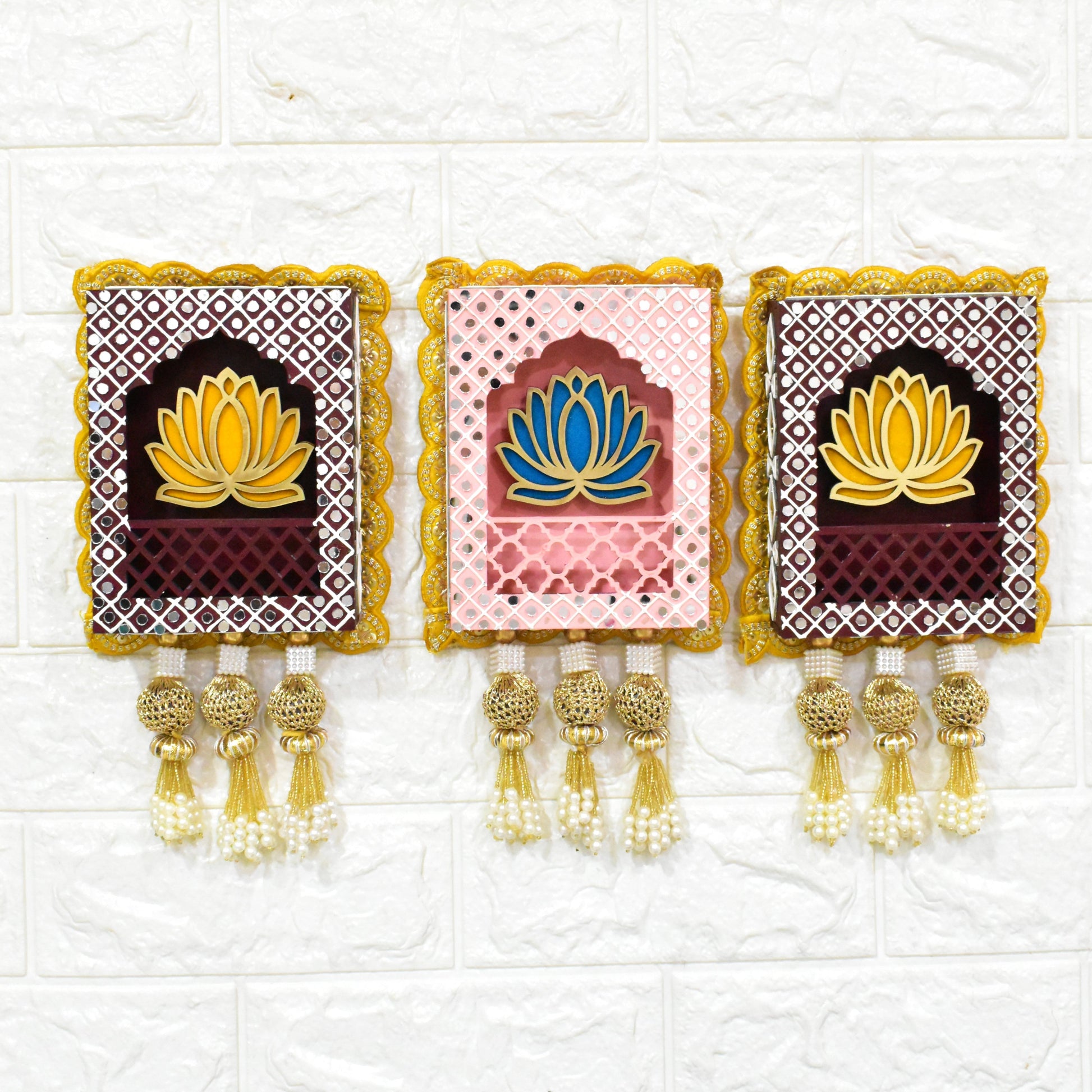 Three rectangular Indian jharokha wall hangings with lotus motifs, decorative patterns, and tassels, displayed against a light background.
