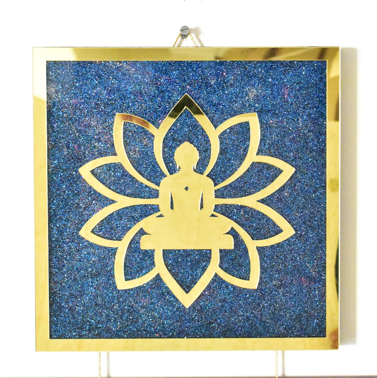 Decorative wall art with gold silhouette of a meditating figure Mahavir God inside a lotus flower on a blue glittery background.
