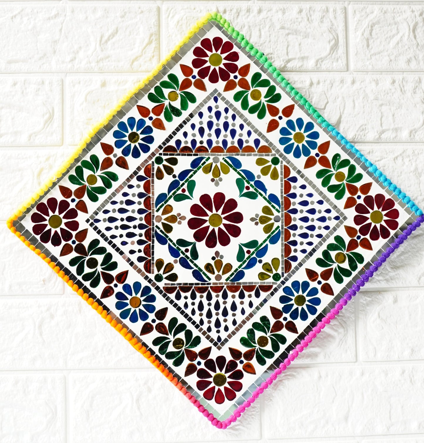 Decorative square tile with colorful floral pattern on a white tiled background
