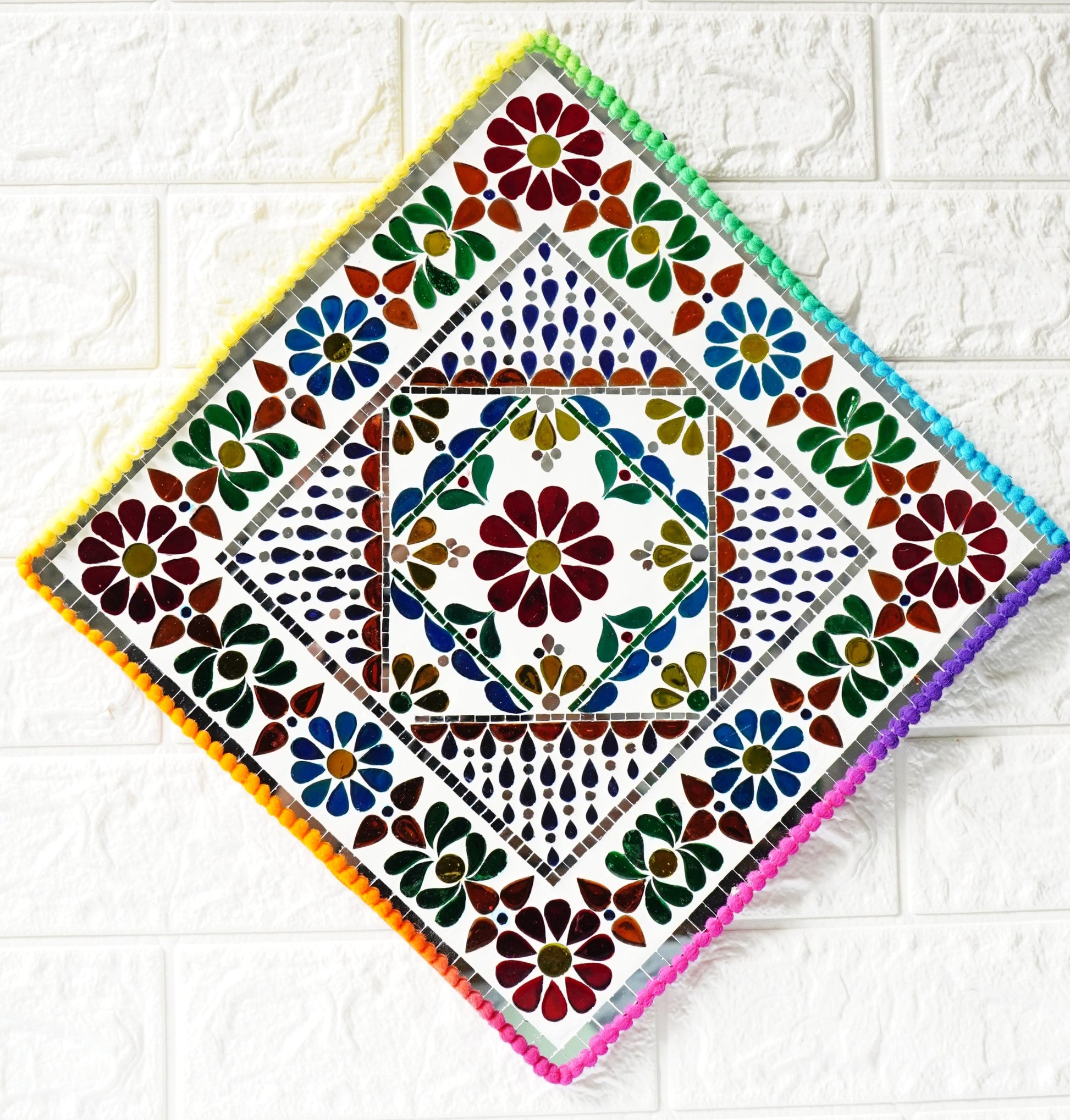 Decorative square tile with colorful floral pattern on a white tiled background