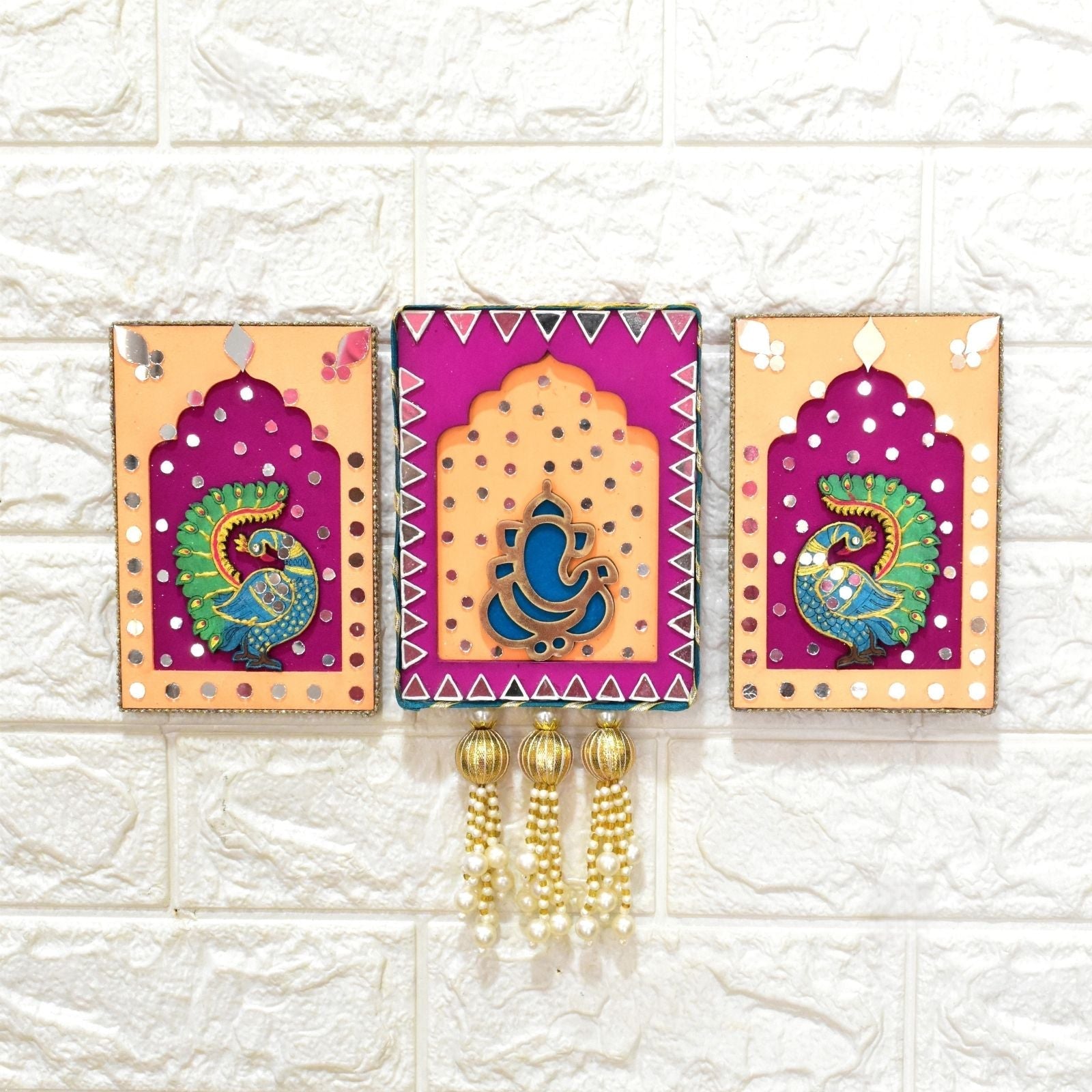 Decorative Pink & Orange handmade Ganesha & Peacock Jharokha Wall Hanging on a white textured wall