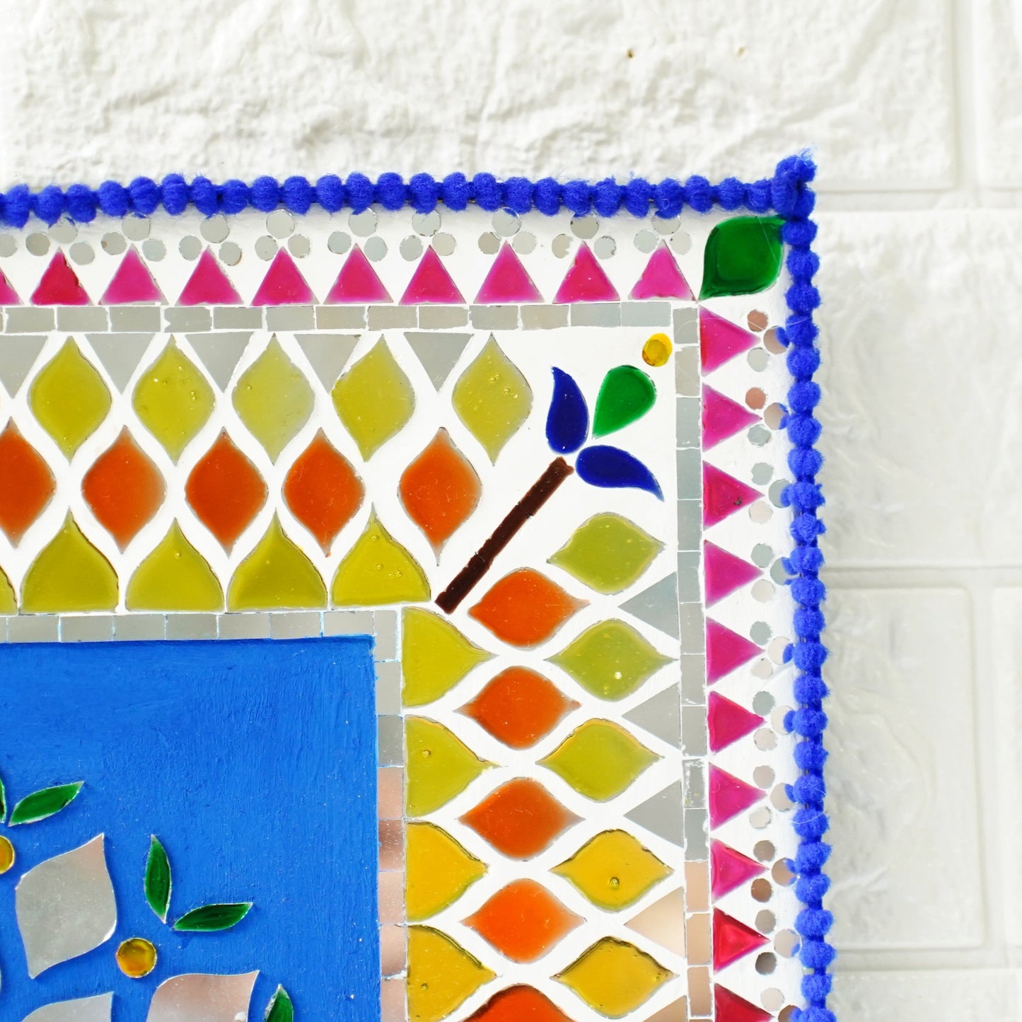 Colorful mirror mosaic art piece on a white tile background