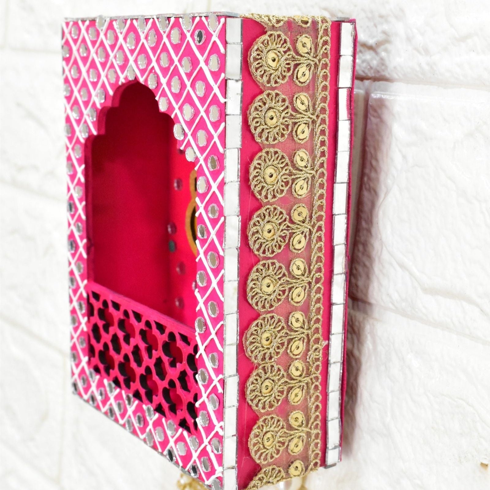 Close up Decorative pink box jharokha wall hanging with gold patterns on a white background