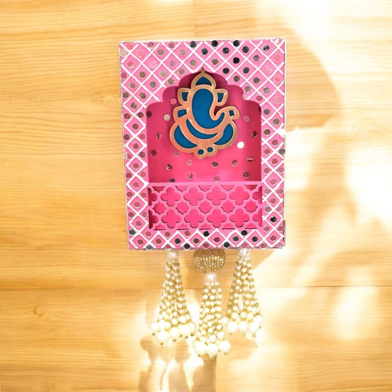 Decorative wall hanging with pink colour and blue Ganesha on a wooden background