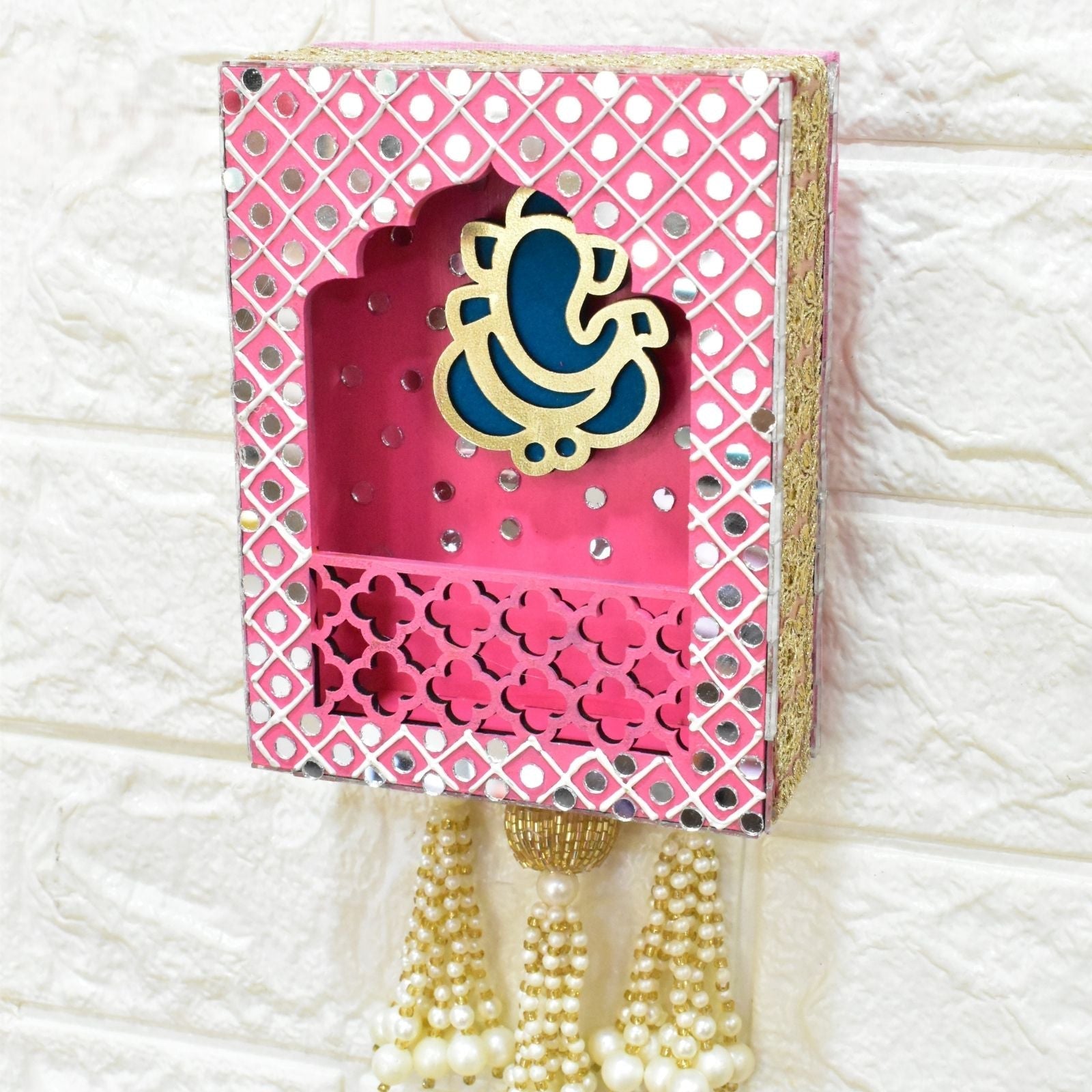 Decorative wall hanging jharokha with pink and blue Ganesha on a textured white background
