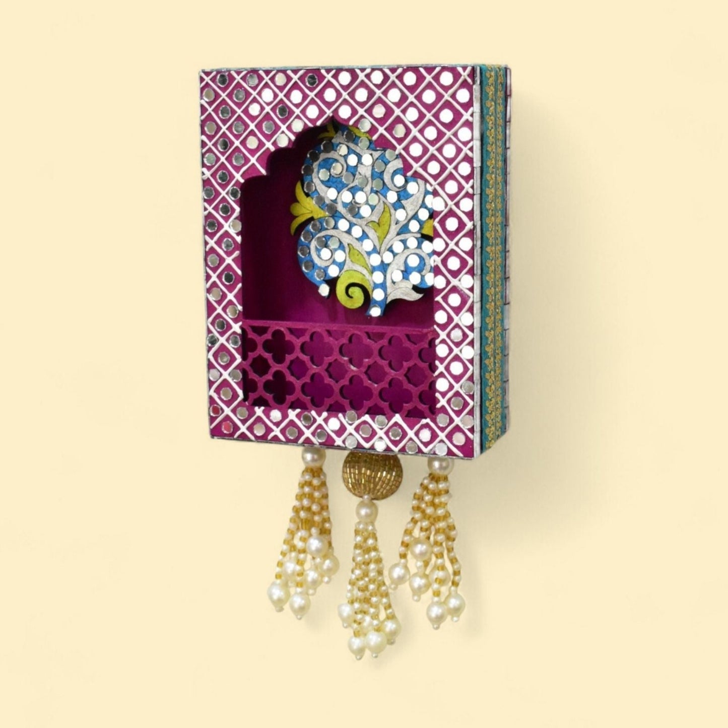 Pink tree wall jharokha with mirror and beads and pearl tassels on a wall.