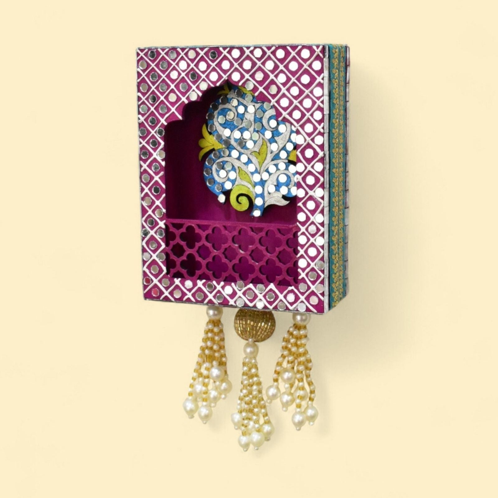 Pink tree wall jharokha with mirror and beads and pearl tassels on a wall.