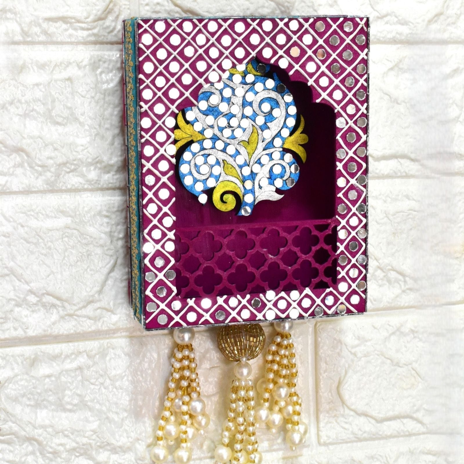 Close up of Pink tree wall jharokha with mirror and beads and pearl tassels on a wall.