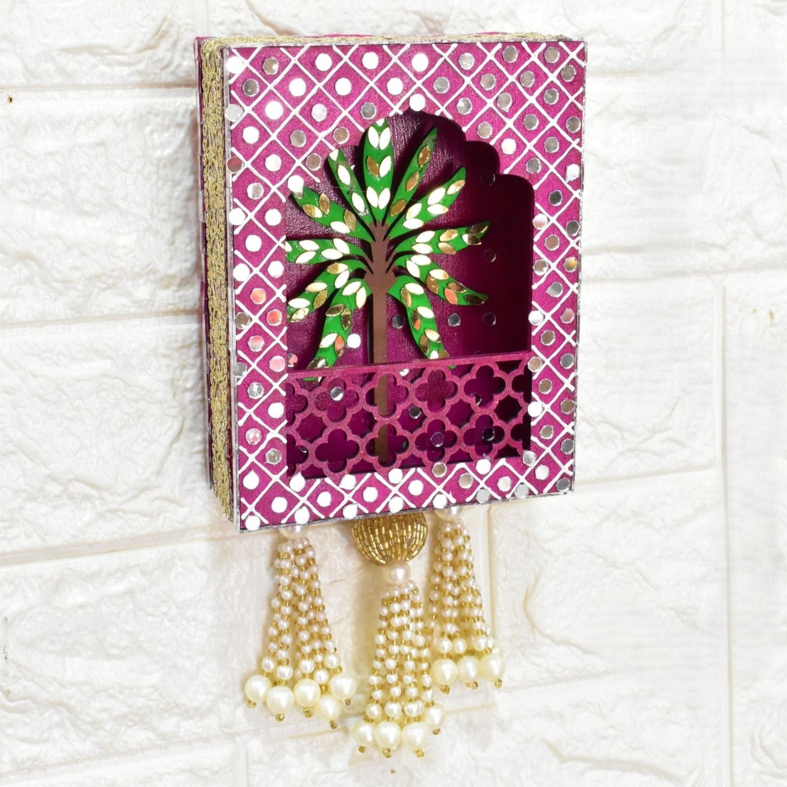 Decorative wall hanging with a tree design on a pink background, featuring tassels.