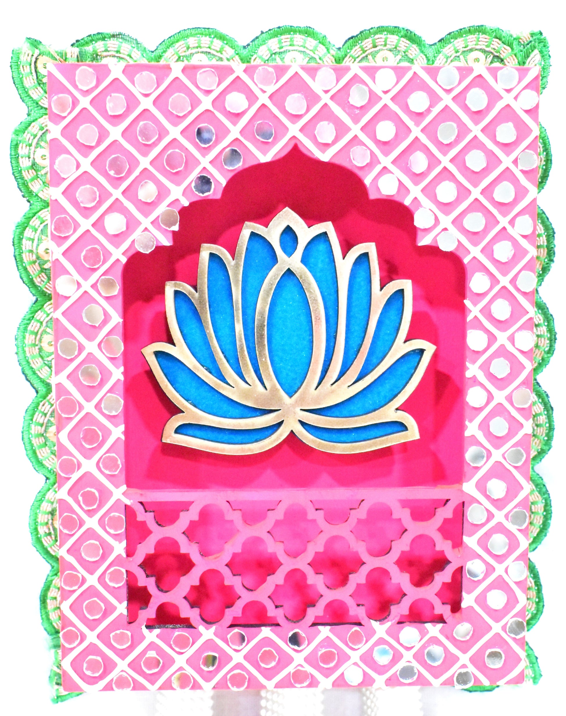 Lotus Jharokha Wall Hanging with a blue lotus flower on a pink and green patterned background, with gold-colored decorative elements and three gold tassels at the bottom.