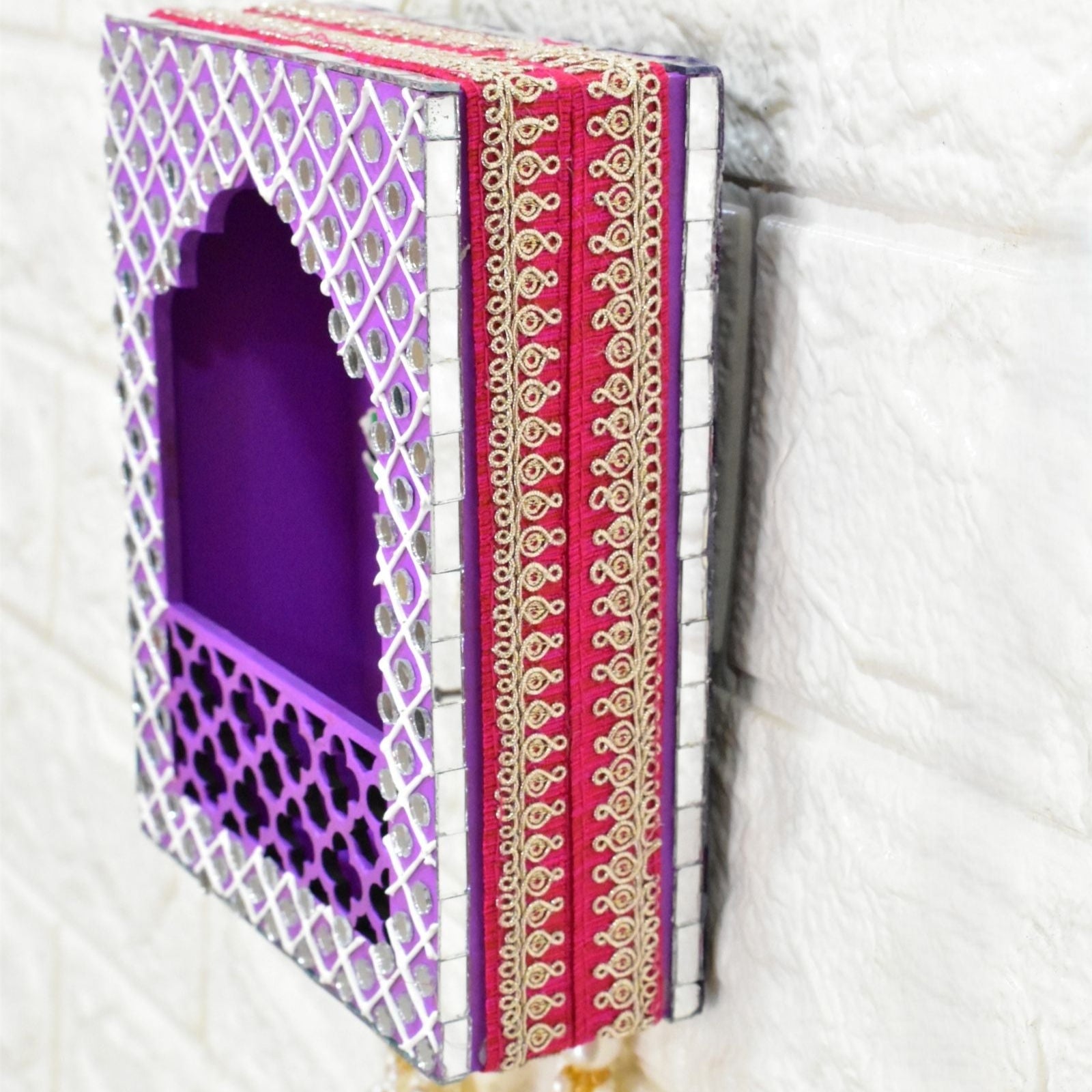 Jharokha wall hanging with purple interior and pink and gold tassels on a white background