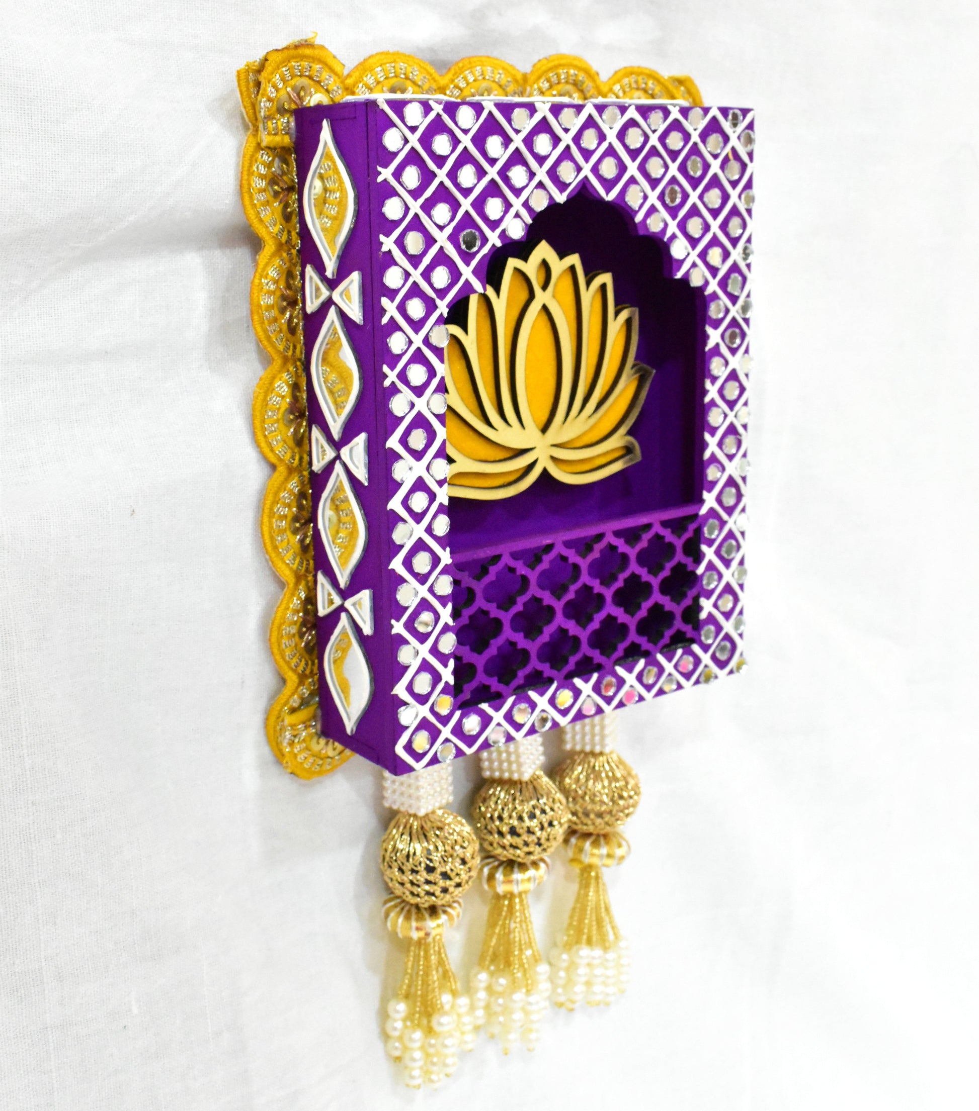 A Handcrafted Lotus Jharokha Wall Hanging with a purple background, yellow lotus flower, and decorative elements including tassels.