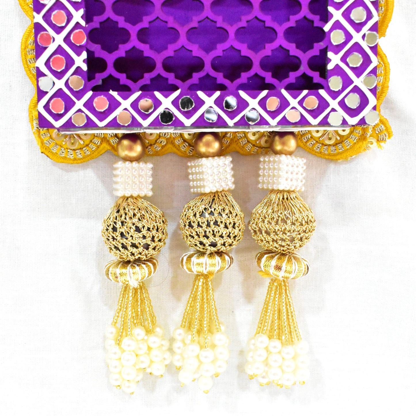 A Handcrafted Lotus Jharokha Wall Hanging with a purple background, yellow lotus flower, and decorative elements including tassels.