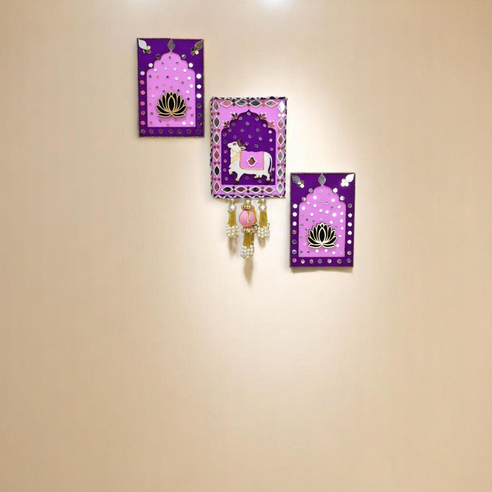 Set of three decorative jharokha with pink & purple borders and centers featuring a cow and lotus design in the living room.