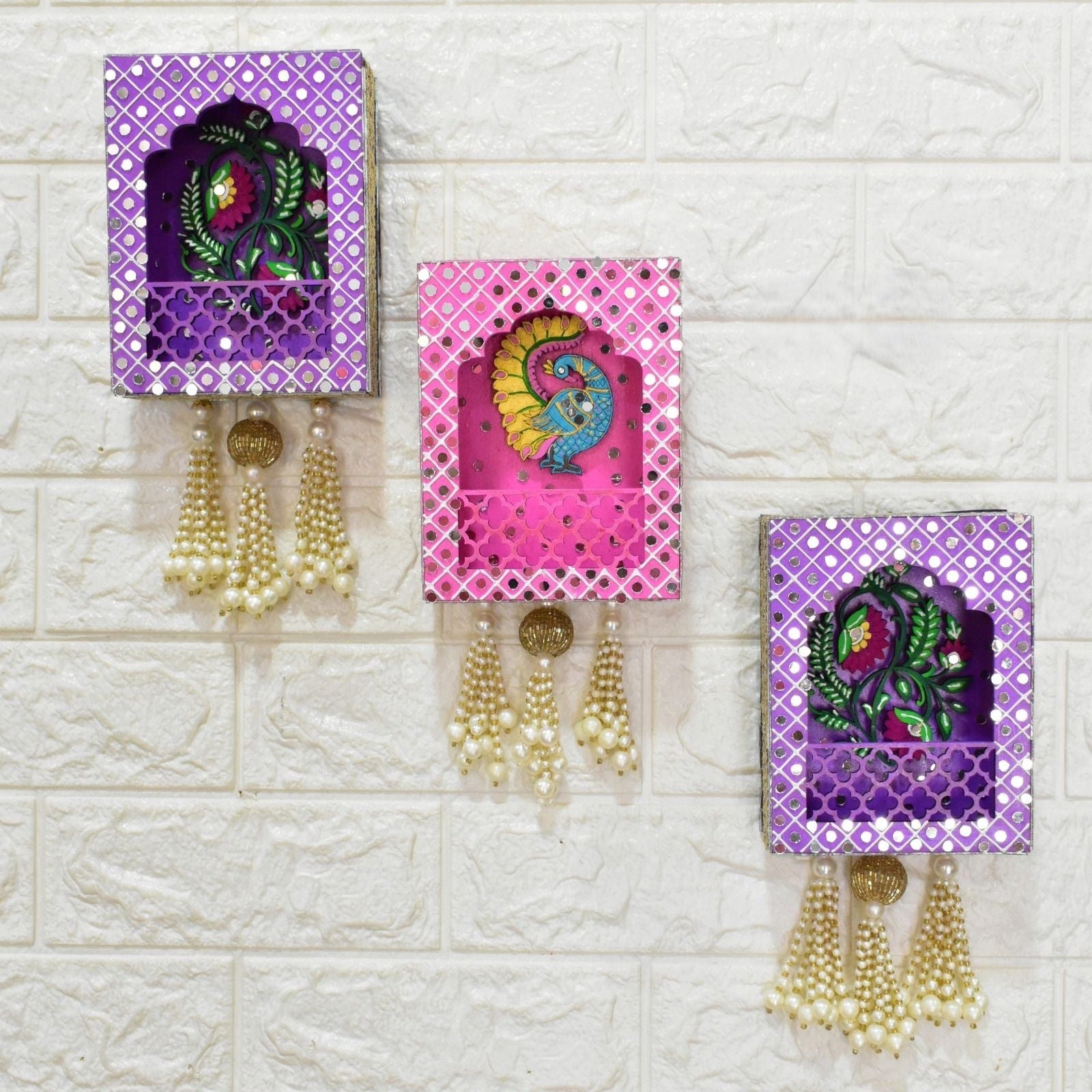 Decorative wall hangings with Peacock and floral design and pearl tassels on a textured white background.