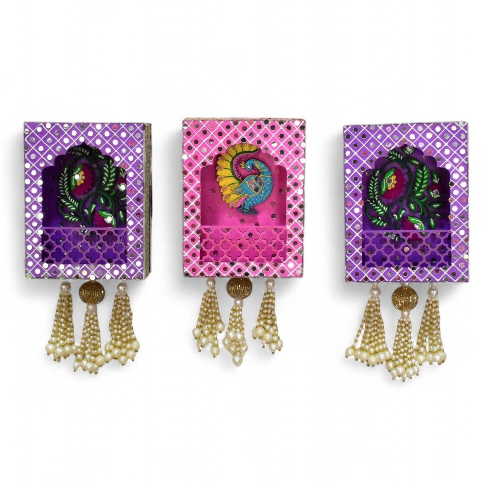 Three decorative wall hangings with peacock and floral design and tassels in pearl and gold on a white background.