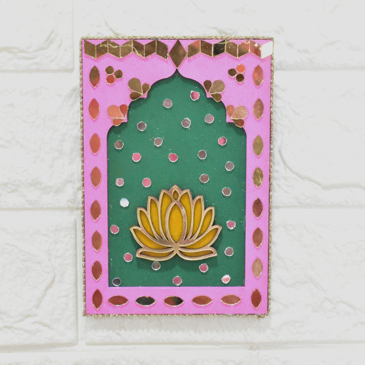 Pink and green wall art with floral design with beads and pearl tassels on a white textured wall