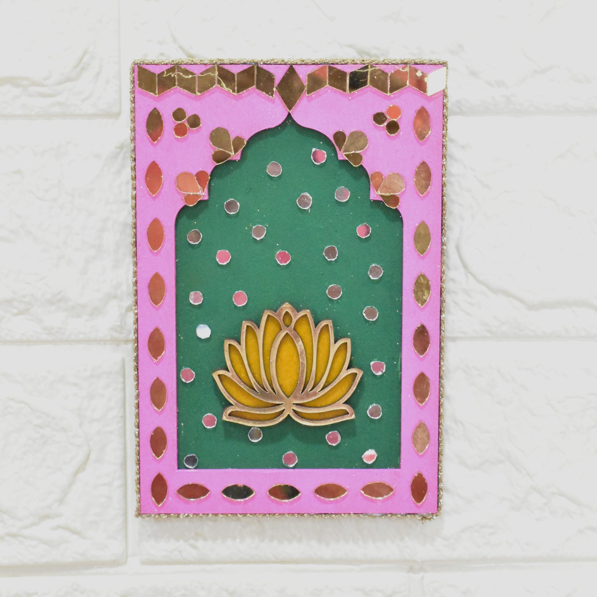 Pink and green wall art with floral design with beads and pearl tassels on a white textured wall