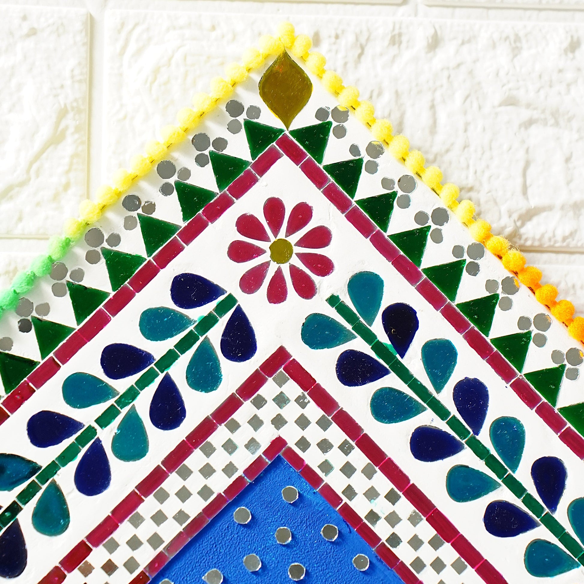 Colorful sun mirror mosaic with floral design on a white textured background